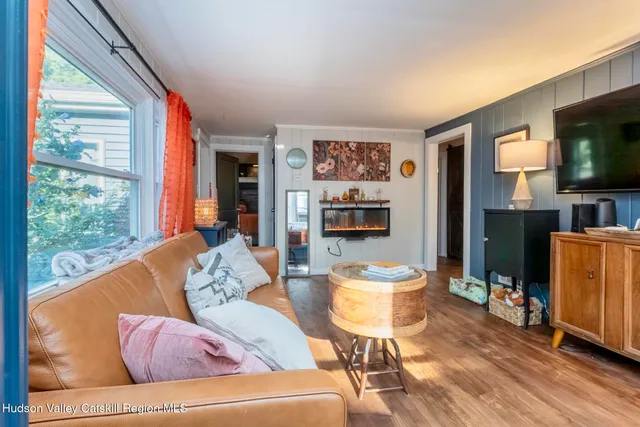 a living room with furniture a flat screen tv and a floor to ceiling window