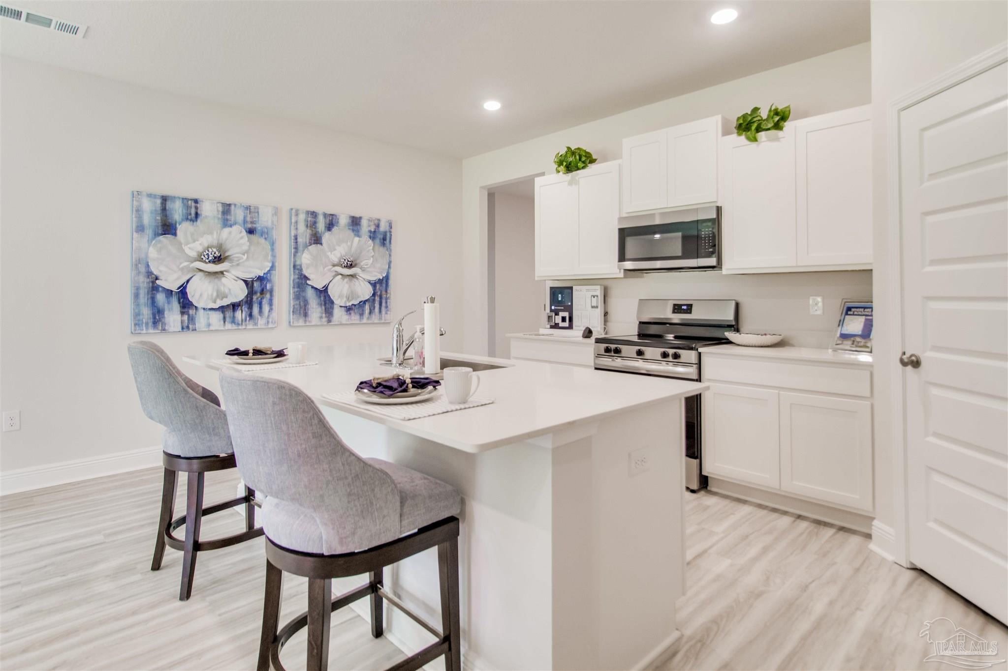 4753 Redhead Court Pace, FL 32571 - Photo 16 of 44 a kitchen with stainless steel appliances a sink a stove a table and chairs