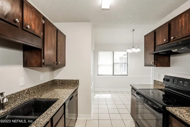 a kitchen with granite countertop wooden cabinets and a stove top oven