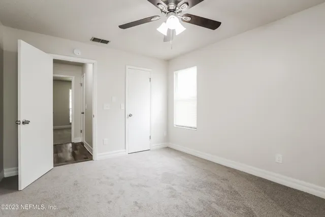 an empty room with closet and a chandelier fan