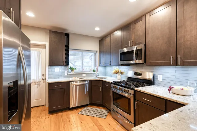 a kitchen with stainless steel appliances granite countertop a stove top oven a sink dishwasher a refrigerator and cabinets with wooden floor