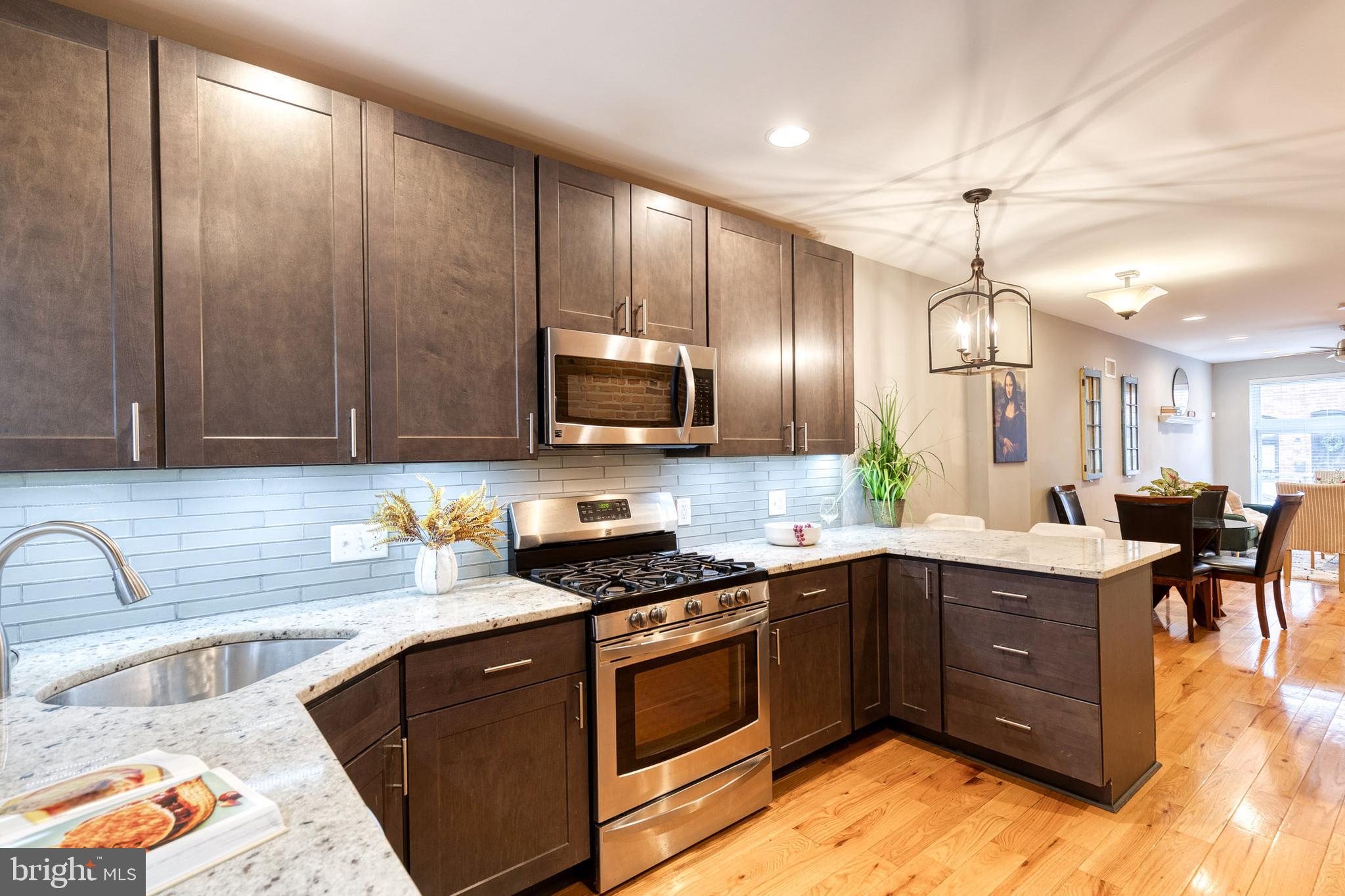 626 South Curley Street Baltimore, MD 21224 - Photo 8 of 23 a kitchen with stainless steel appliances granite countertop wooden cabinets a sink dishwasher a stove and a refrigerator with wooden floor