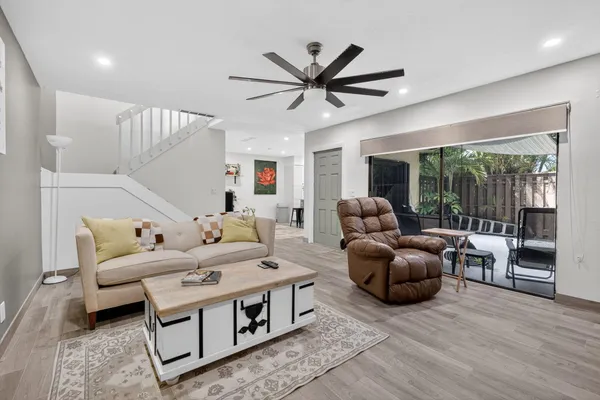 a living room with furniture a ceiling fan and a large window