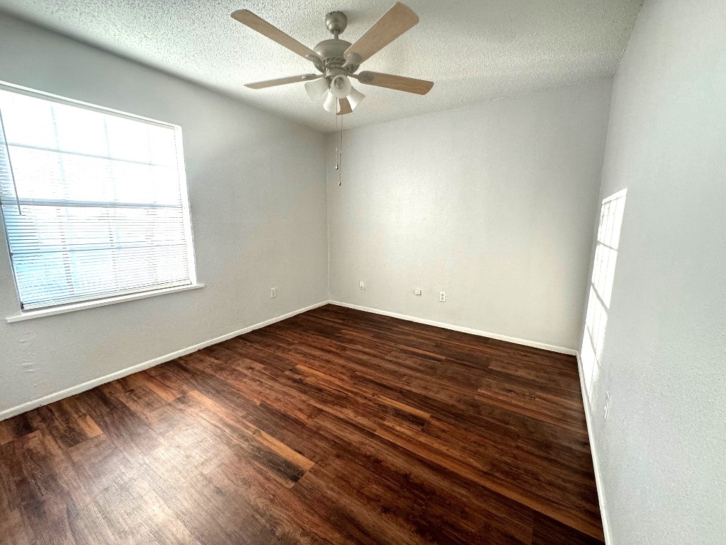 1307 Center Street Lockhart, TX 78644 - Photo 11 of 14 an empty room with wooden floor fan and windows