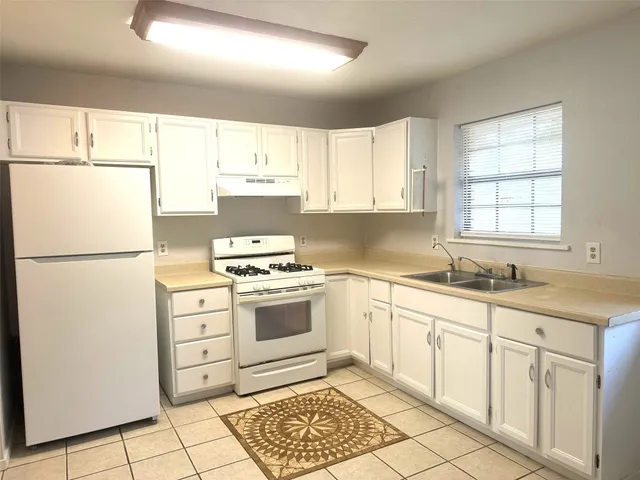 a kitchen with cabinets appliances a sink and a counter top space