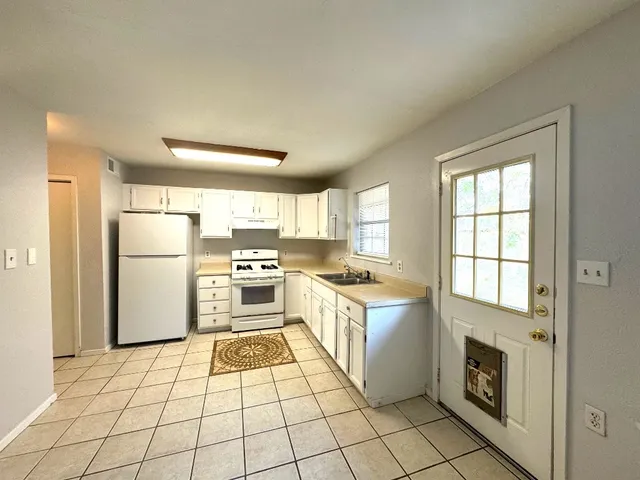a kitchen with a stove a refrigerator and white cabinets