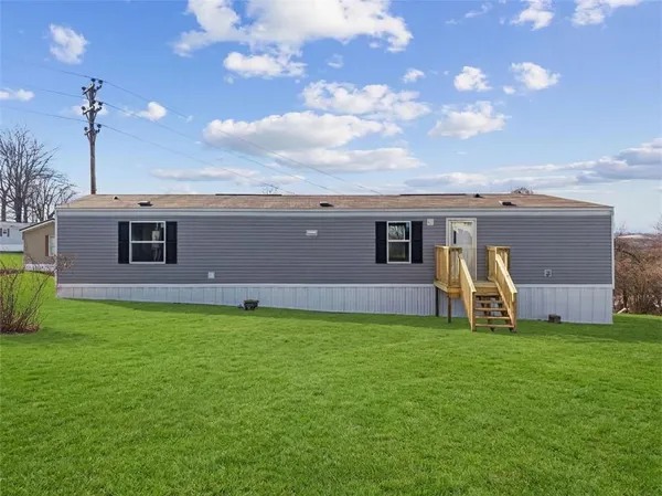 a view of a house with a yard and a large tree