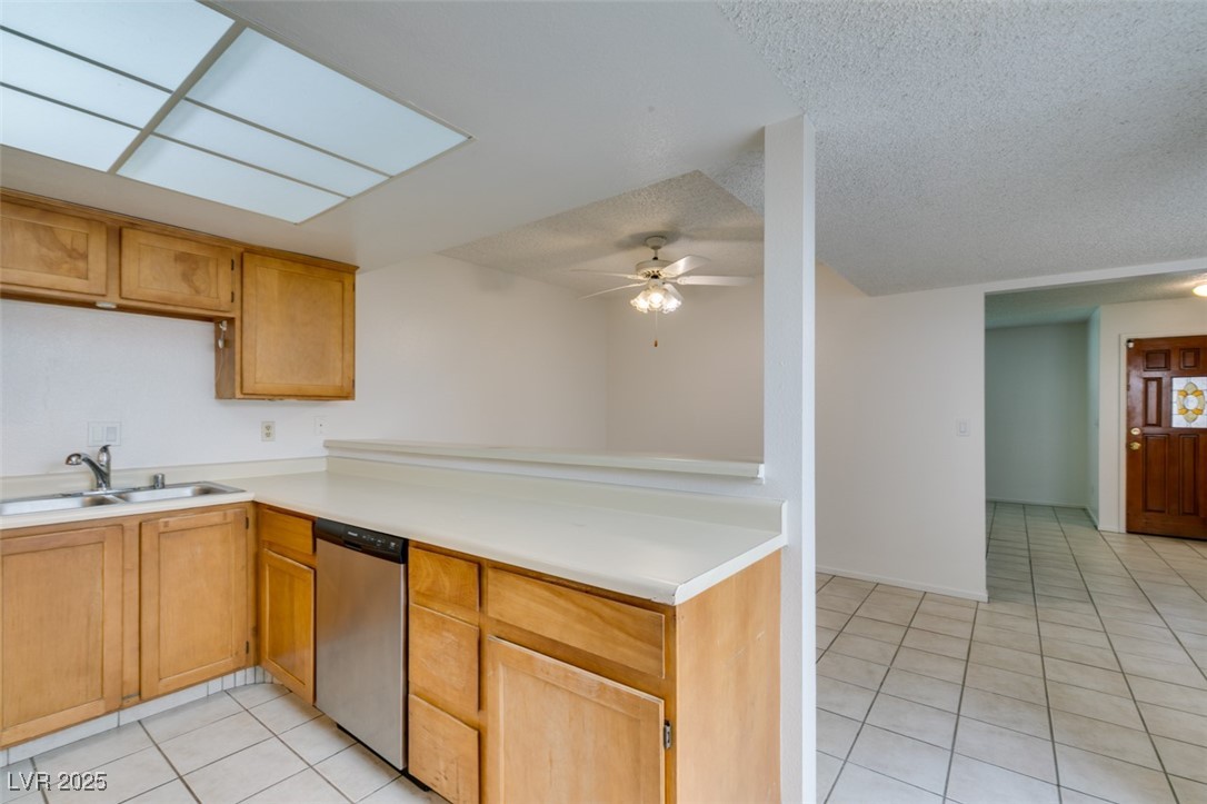 2681 Ruthe Duarte Avenue Las Vegas, NV 89121 - Photo 26 of 43 Kitchen featuring ceiling fan, stainless steel dishwasher, light tile patterned flooring, a sink, and light countertops