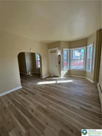 a view of empty room with wooden floor and fan