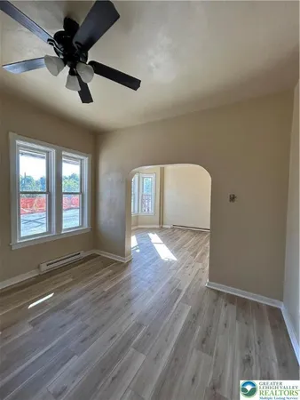 a view of empty room with wooden floor and fan