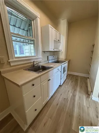a kitchen with granite countertop white cabinets and wooden floor