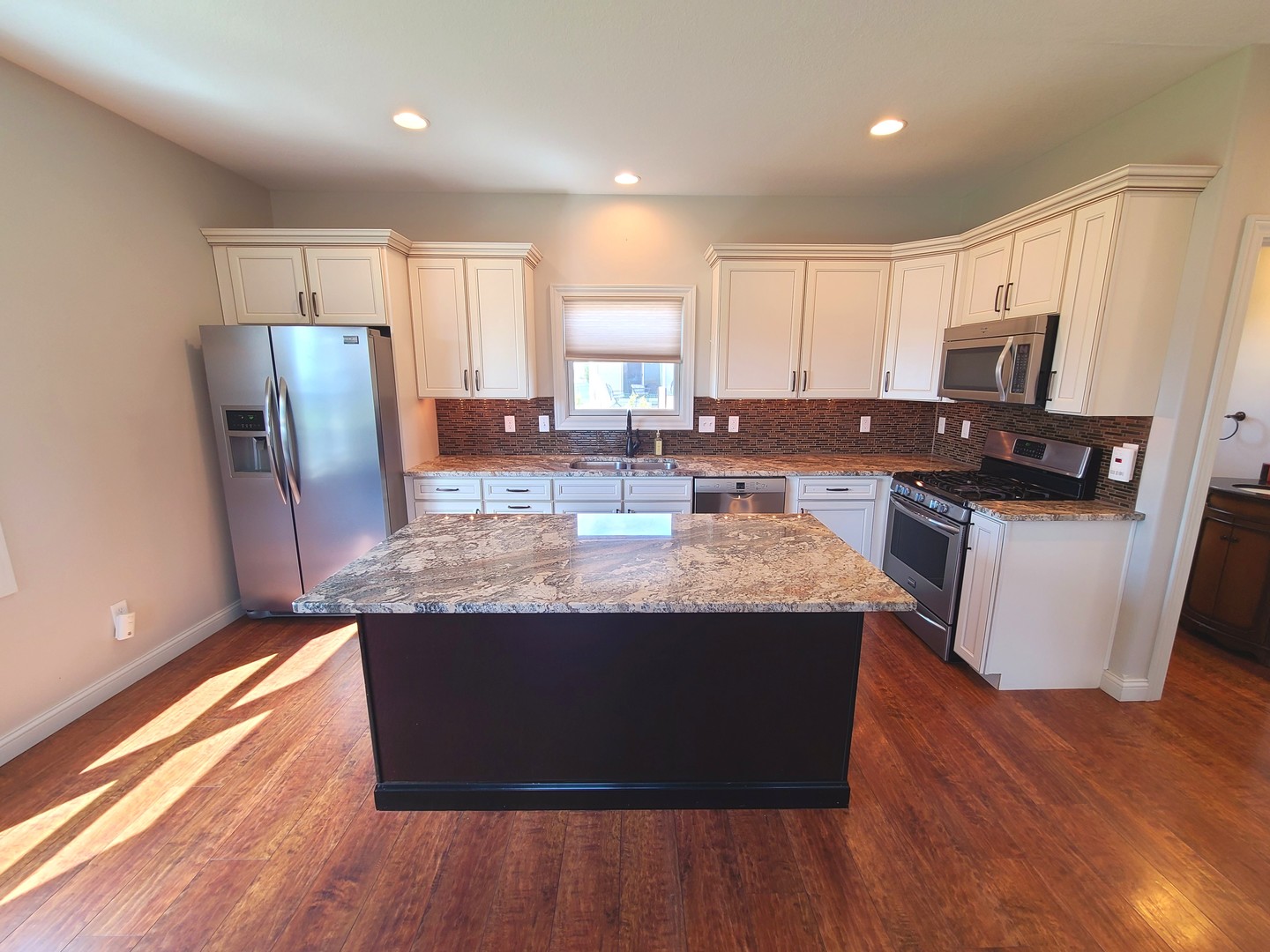 790 Muirfield Circle Eldridge, IA 52748 - Photo 8 of 36 a kitchen with kitchen island granite countertop wooden floors and stainless steel appliances