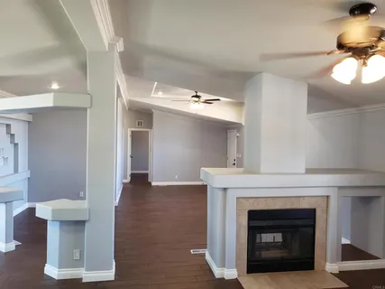 a view of an empty room with wooden floor and a fireplace