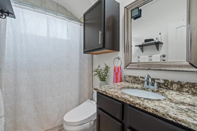 a bathroom with a granite countertop sink toilet and mirror