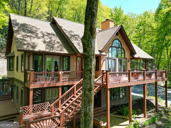 a backyard of a house with a table and chairs under a large tree