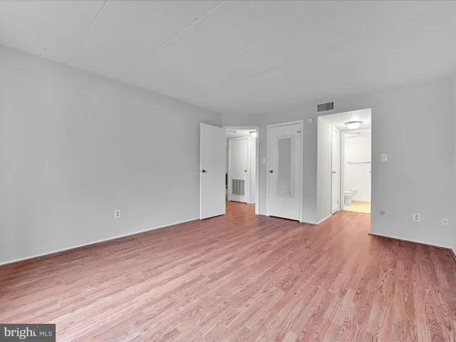 a view of an empty room with wooden floor and closet