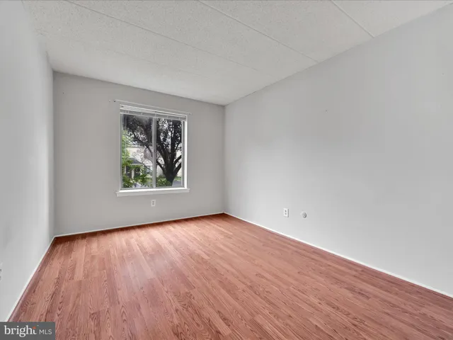 an empty room with wooden floor and window