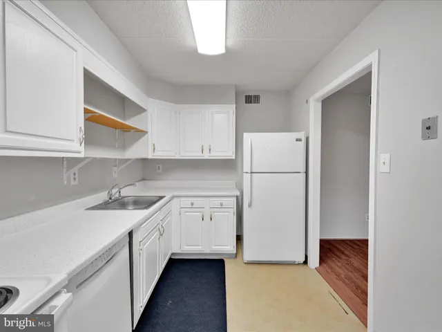 a kitchen with a sink a refrigerator and white cabinets
