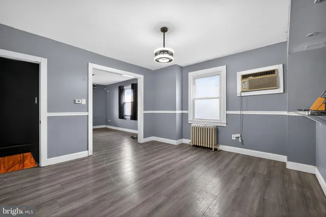 an empty room with wooden floor chandelier and windows