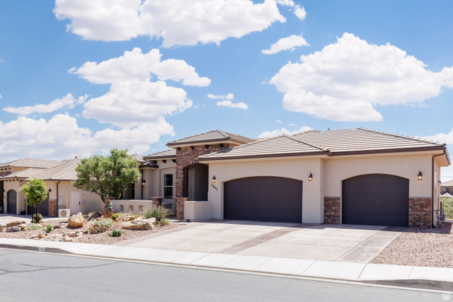 2005 West 450 S Circle St. George, UT 84770 - Photo 3 of 57 Contemporary stucco exterior featuring stone accents, a tile roof, and arched garage doors
