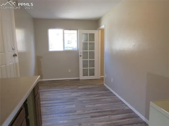 a view of an empty room with wooden floor and a window