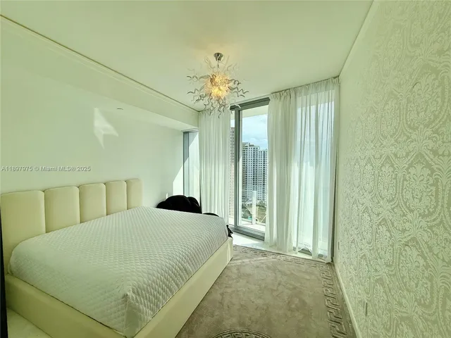 a bedroom with a large bed and a chandelier