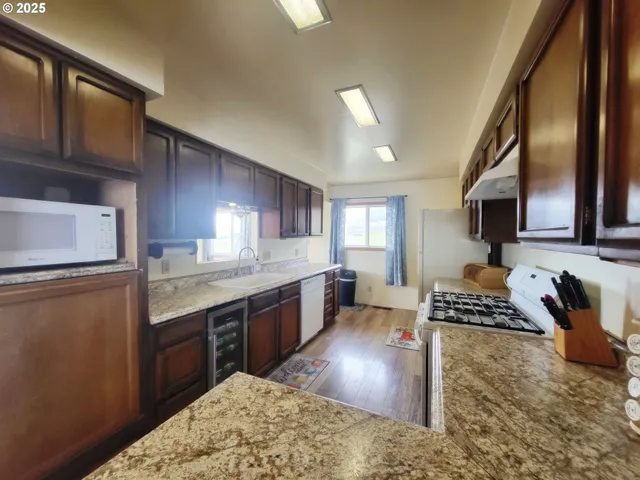 a kitchen with stainless steel appliances granite countertop a stove a sink dishwasher a microwave oven and a dining table with wooden cabinet