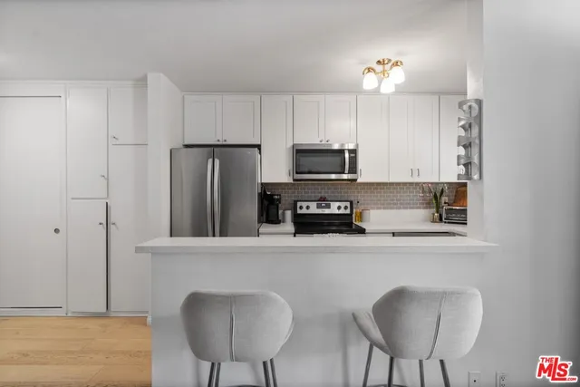 a kitchen with stainless steel appliances a refrigerator a stove a sink cabinets and a dining table