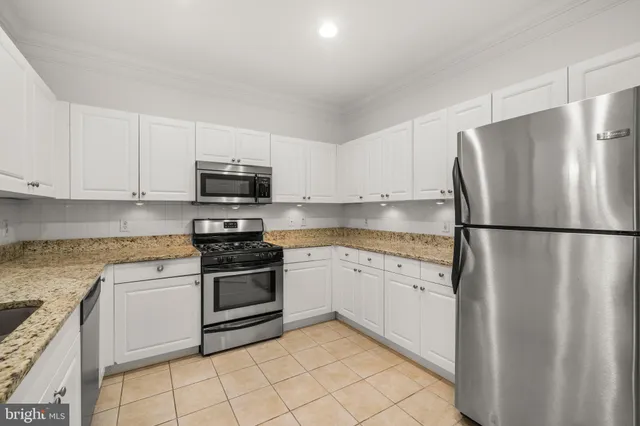 a kitchen with granite countertop a refrigerator and a stove top oven