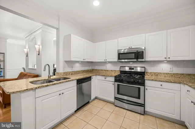 a kitchen with stainless steel appliances granite countertop a sink and dishwasher a stove top oven with white cabinets