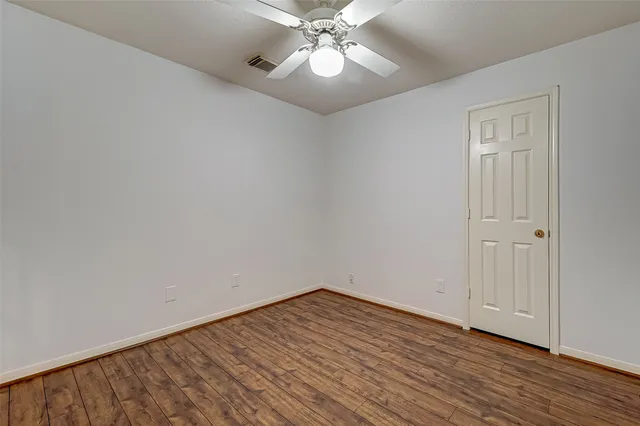 an empty room with wooden floor fireplace and windows
