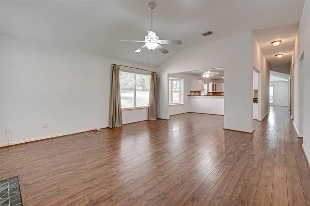 a view of a big room with wooden floor and a kitchen