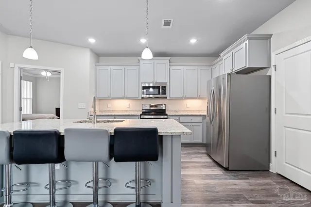 a kitchen with stainless steel appliances granite countertop a stove refrigerator sink cabinets dining table and chairs