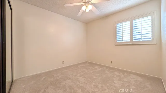 an empty room with a chandelier fan and windows