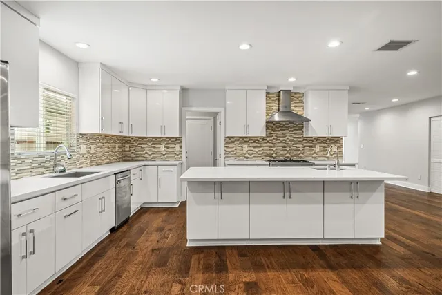 a kitchen with kitchen island granite countertop a sink cabinets and wooden floor