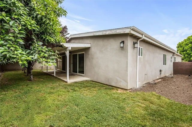 a backyard of a house with plants and large tree