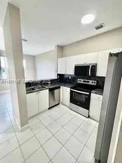 a kitchen with granite countertop white cabinets and black appliances