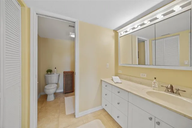 a bathroom with a granite countertop toilet sink and mirror