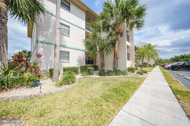 a front view of yellow house with a yard and potted plants