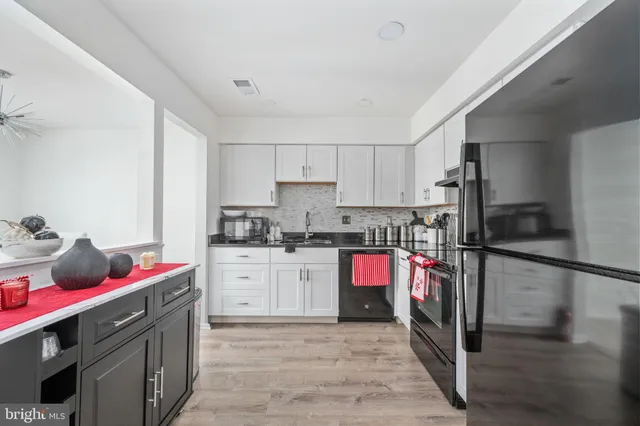 a kitchen with granite countertop a refrigerator stove and wooden floor