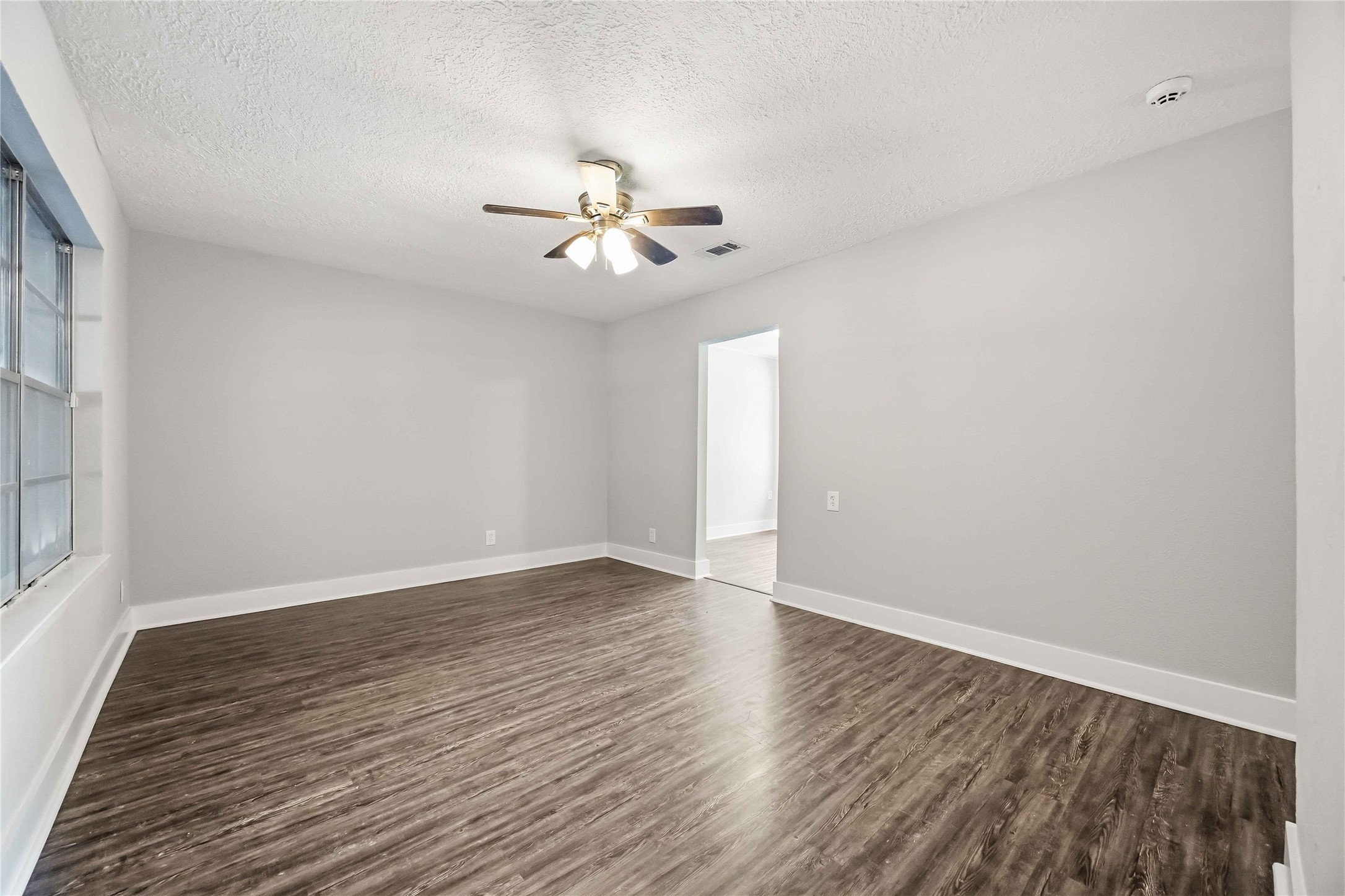 113 East Witcher Lane Houston, TX 77076 - Photo 5 of 21 a view of an empty room with wooden floor and a ceiling fan