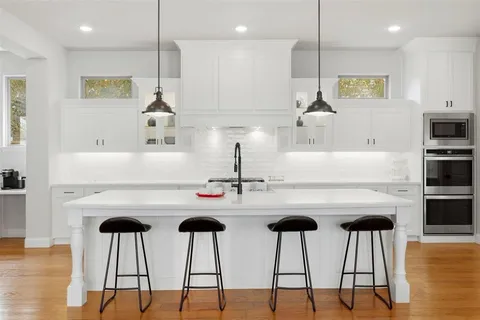 a kitchen with kitchen island a stove a table and chairs in it