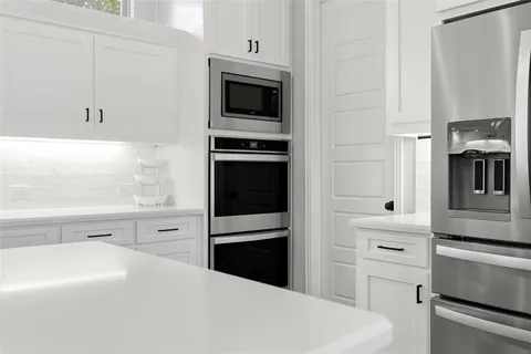 a kitchen with a refrigerator stove and white cabinets
