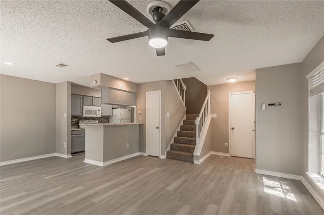 a view of kitchen and empty room with wooden floor