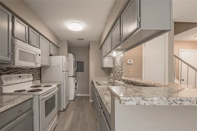 a kitchen with granite countertop a sink stainless steel appliances and cabinets