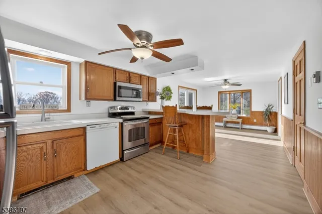 a kitchen with stainless steel appliances granite countertop a refrigerator a stove top oven a sink dishwasher and white cabinets with wooden floor
