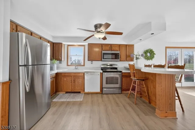 a kitchen with kitchen island granite countertop a refrigerator a stove top oven a sink dishwasher and white cabinets with wooden floor