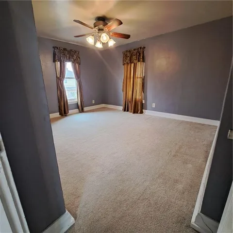 a view of empty room with window and ceiling fan