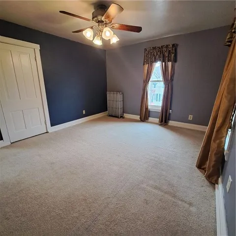 an empty room with a chandelier fan and windows
