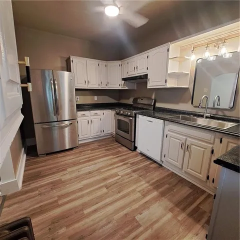 a kitchen with granite countertop a refrigerator stove top oven and sink